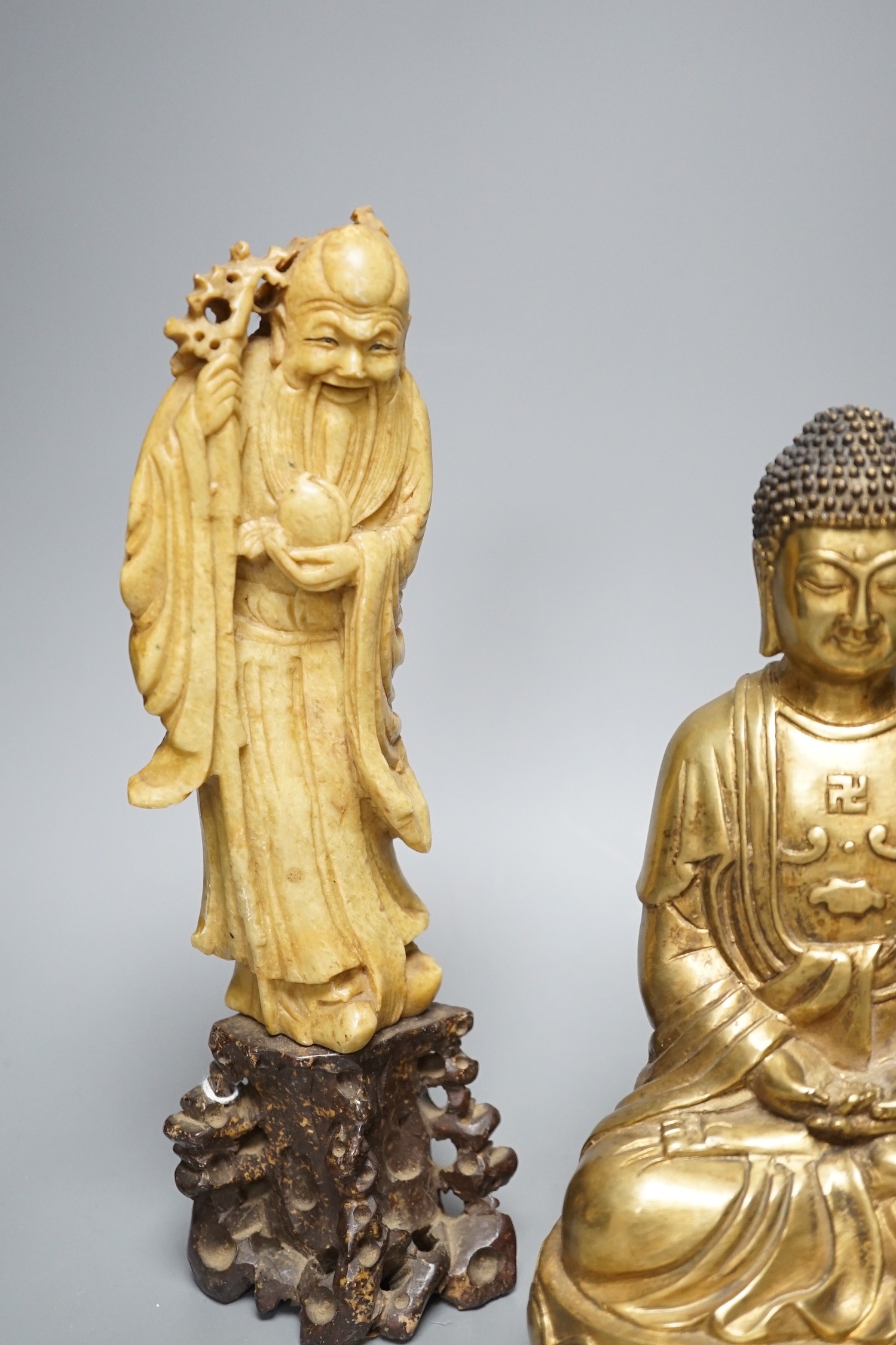 A Chinese greenstone Buddha, a soapstone carving of Shou Lao on carved hardwood stand, and a bronze figure of a seated Shaykamuni Buddha, tallest 29cm